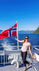 A young woman leaning on a rail of a ship with a Norwegian flag waving behind him, Songefjorden...