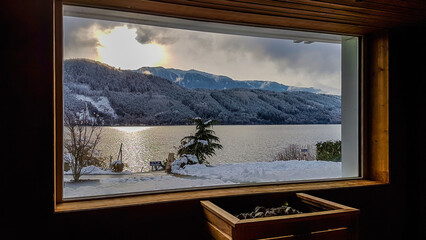 Alpine sauna with the view on the lake and the mountains. Under the window there is a furnace,...