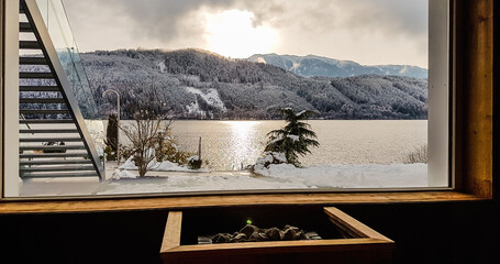 Alpine sauna with the view on the lake and the mountains. Under the window there is a furnace,...
