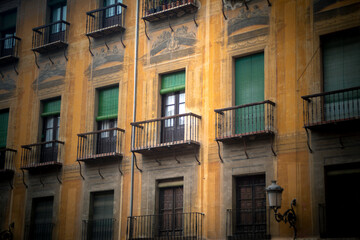 Fototapeta na wymiar Beautiful facade of an old building in the cathedral square of Granada, Spain. Renaissance style facade with trompe l'oeil, latticed balconies and typical Spanish green shutters
