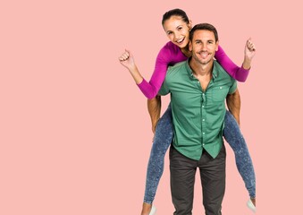 Portrait of caucasian man giving a piggy back ride to his wife against copy space on pink background