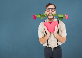 Caucasian man with roses in his mouth holding a red heart against copy space on blue background