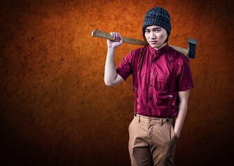 Portrait of asian young man holding an axe against orange textured grunge background