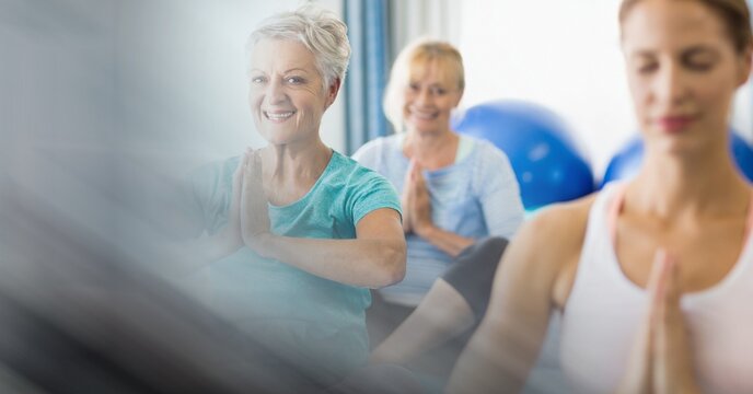 Blur effect with copy space against female yoga trainer and group of senior people performing yoga