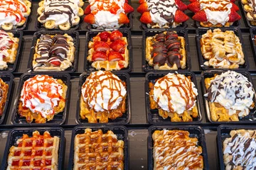 Foto op Aluminium Delicious traditional Liege waffles with colorful toppings on display in a store window in Brussels, Belgium. Sugary desserts. Typical Belgian sweet food. © BooFamily