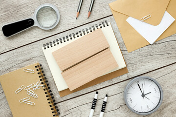 On a light background, an envelope, a magnifying glass, a pen and an empty notepad with wooden...