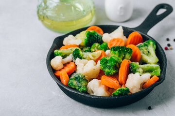 Frozen vegetables. Frozen carrots, broccoli and cauliflower in cast iron pan ready to cook