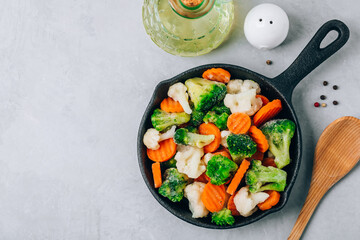Frozen vegetables. Frozen carrots, broccoli and cauliflower in cast iron pan ready to cook