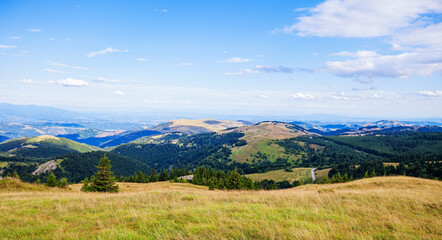 Beautiful nature panoramic view of mountain range. Peaceful landscape. Green hills and fields on summer day. Blue sky with clouds. Panorama of Kopaonik mountain. Serbia. Europe.