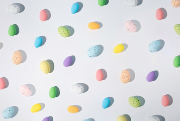 Artificial styrofoam eggs of various colors on white background with sharp shadow.