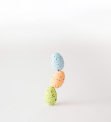 Three colorful styrofoam eggs stacked on white background.