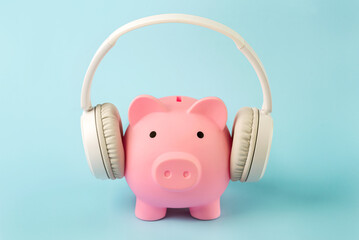Pink piggy money bank with white wireless headphones