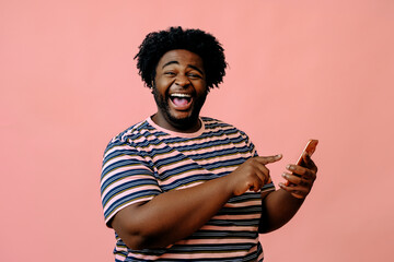young african american man with a phone posing in the studio over pink background