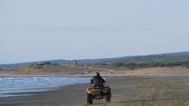 A man drives away in an ATV vehicle along the sandy beach of Ayia Eirini in Cyprus
