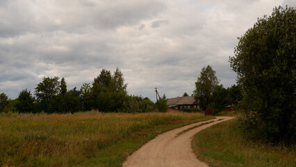 Fototapeta na wymiar Beautiful rustic summer landscape with road. Old wooden log houses. Vologda region
