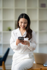 Fototapeta premium Attractive looking Asian business woman using a smartphone. to wipe email and work online via mobile