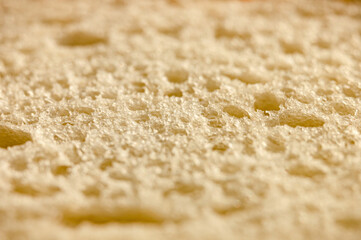 texture of white bread as a close up background. backdrop of rough dappled textured surface slice of loaf or sandwich dough of natural organic food with holes. top view. depth of field