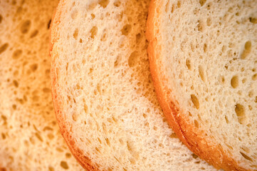 texture of slices white bread as a close up background. backdrop of rough dappled textured surface chopped pieces loaf of natural organic food with holes. top view