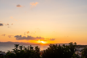 Beautiful sunset over the sea with a view at palms on the beach