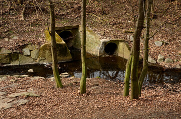 Sewer bridge through a ditch by the road. concrete hole with surroundings of stone paving. grassy...