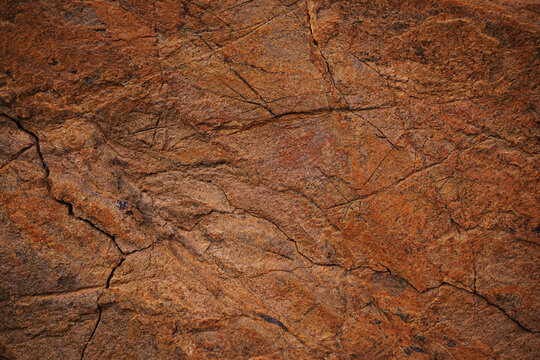 Red brown rock texture. Cracked mountain surface. Close-up. Stone background with space for design.