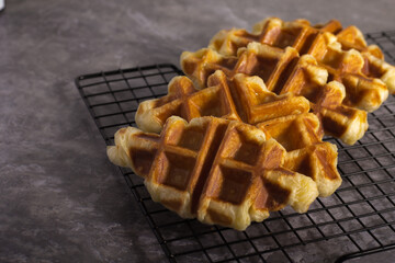 Golden Croffle waffles cooling on a wire rack with a textured gray background.