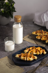 Breakfast scene with Croffle waffles on a blue tray, complemented by a serving of fresh milk.
