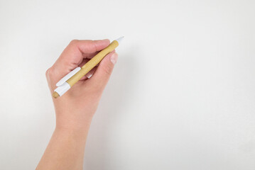 Close-up of a woman's hand holding a pen and writing gesture on a white background