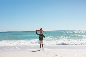African american girl enjoying sunny day on father's shoulders standing at beach, copy space