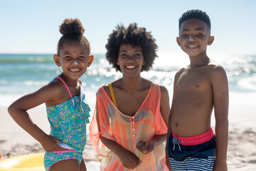 Portrait of happy african american mother amidst children with suntan lotion on noses at beach