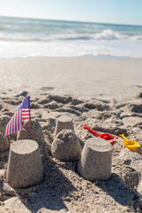America flag with sandcastle on shore at beach during sunny day