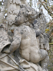 Barocke Steinstatue einer sich anschmiegenden Putte (Engel in Kindgestalt) im Schloßgarten Veitshöchheim (Bayern, Deutschland)