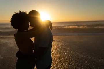 Fotobehang Romantic african american couple spending leisure time together at beach during sunset © WavebreakMediaMicro