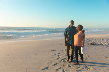 Fototapeta premium Full length of african american senior couple walking at beach against sky with copy space