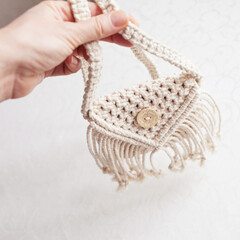 Handmade white macrame bag on the white wall, ECO friendly. Hobby knitting handmade macrame. Modern summer concept.