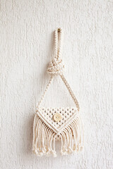 Handmade white macrame bag on the white wall, ECO friendly. Hobby knitting handmade macrame. Modern summer concept. 