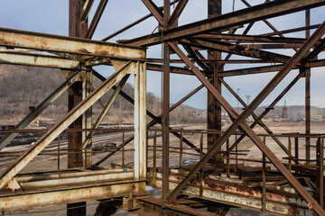 Steel structures meeting at center in front of remains of an industrial park