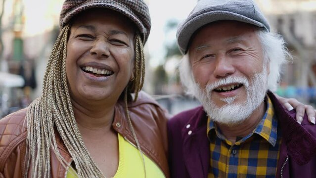 Happy multiracial senior couple having fun in city - Elderly people and love relationship concept