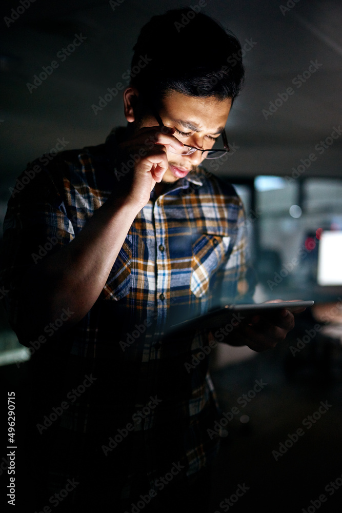 Poster Is this data correct. Shot of a male designer working on a digital tablet late in the office.