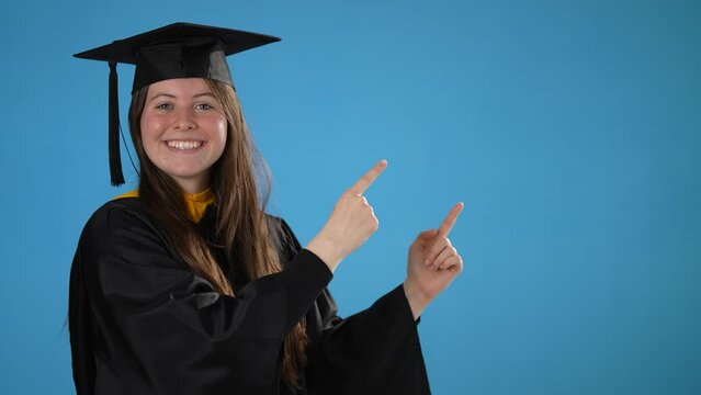 Graduate girl pointing to copy space, blank, success on blue background, celebrating graduation from the high school or University, excited dancing party