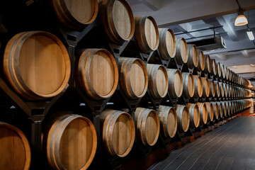 Old aged traditional wooden barrels with wine in a vault lined up in cool and dark cellar in Italy, Porto, Portugal, France