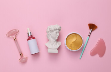 David bust and skin care products on a pink background. Skin care concept. Top view. Flat lay
