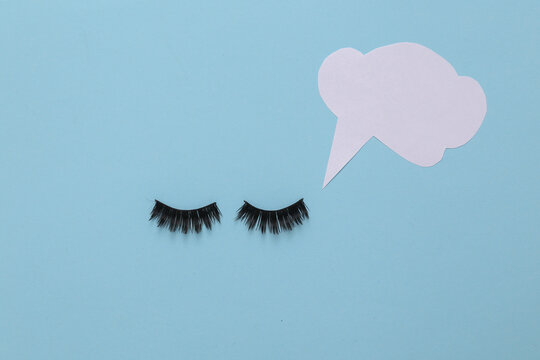 False eyelashes with dialog cloud on blue background. Minimal still life