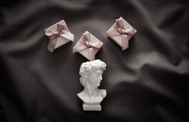 David plaster bust with gift boxes on gray crumpled silk background