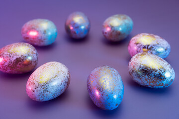 Side view round frame made of Easter golden eggs with different patterns in neon colors light. Purple very peri color minimalist festive background. Modern trendy Easter. Selective focus. Copy space.