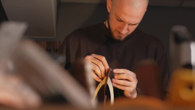 tanner makes leather product, purse. With your own hands, DIY instruction, indoor, closeup, lifestyle, authentic. Eco production, entrepreneur. sews with threads