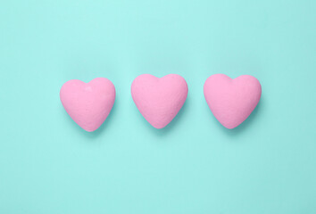 Three pink hearts on blue background. Minimal love still life