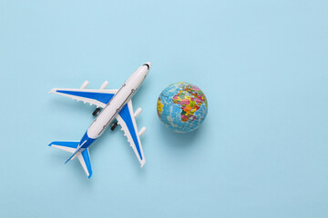 Toy model airplane with globe on blue background. Travel concept. Flat lay, top view