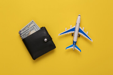 Passenger plane and wallet with money on a yellow background. Travel concept. Top view