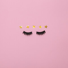 Excellent beauty service.  False eyelashes with 5 gold stars on pink background. Top view